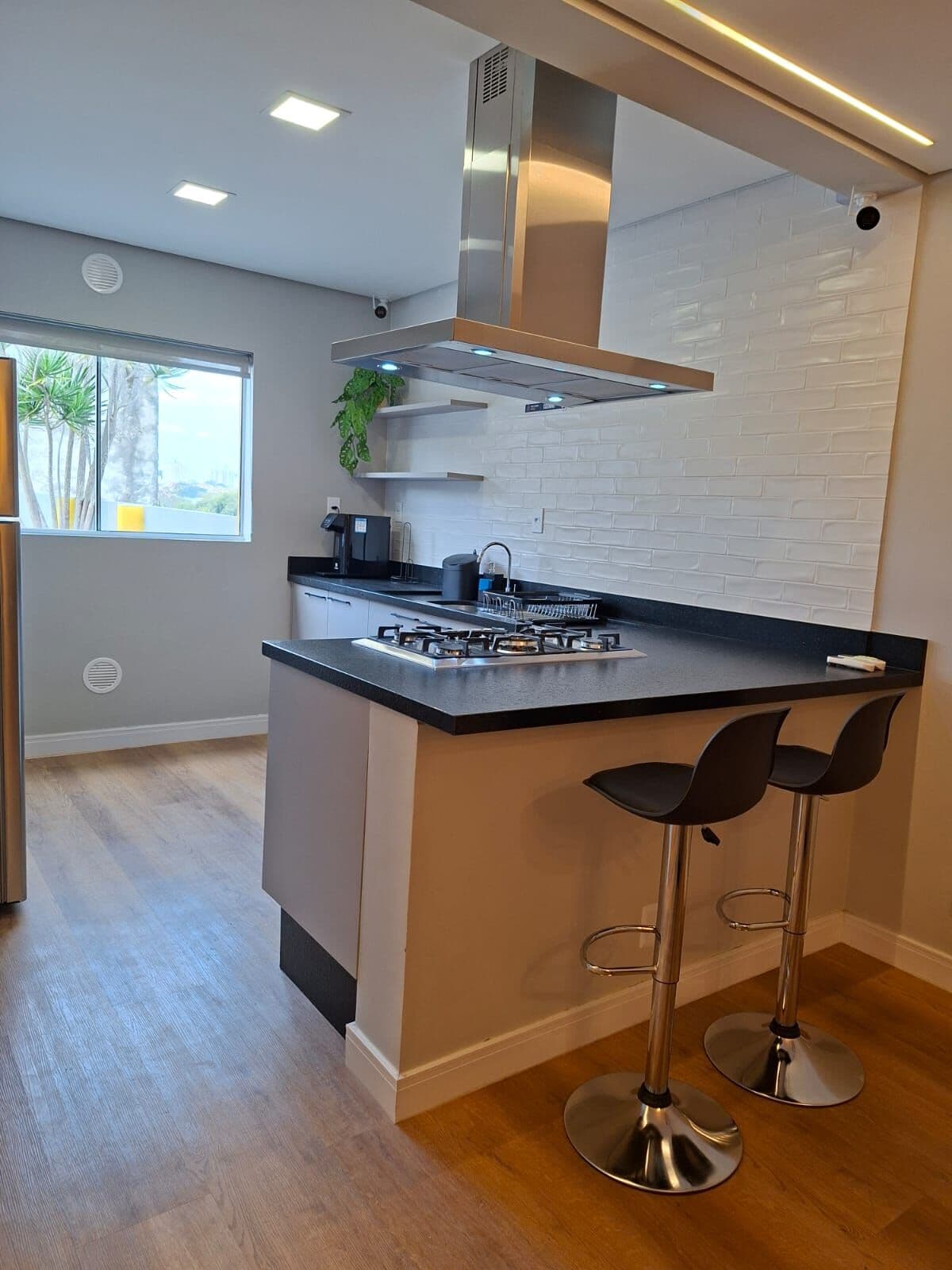 Cozinha com ilha, cooktop e banquetas