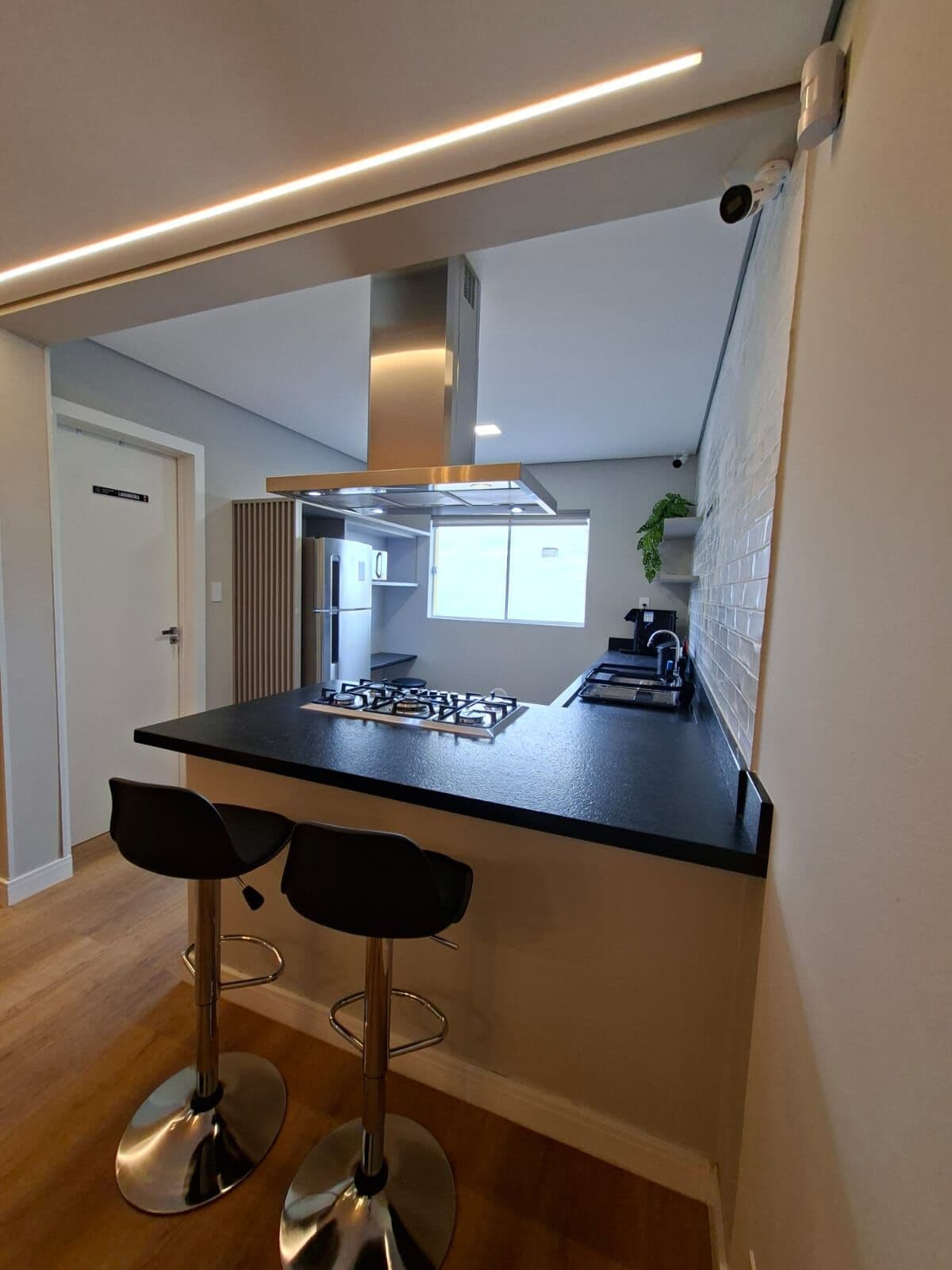Ilha da cozinha com coifa e banquetas