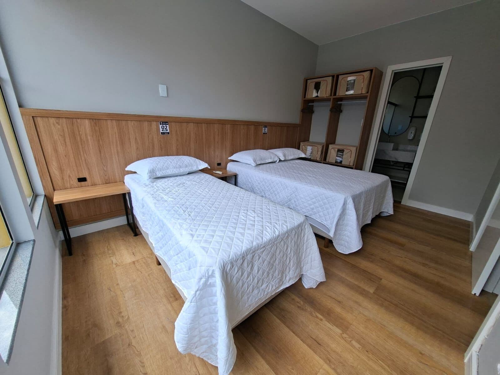 Quarto com duas camas de solteiro e cabeceira de madeira