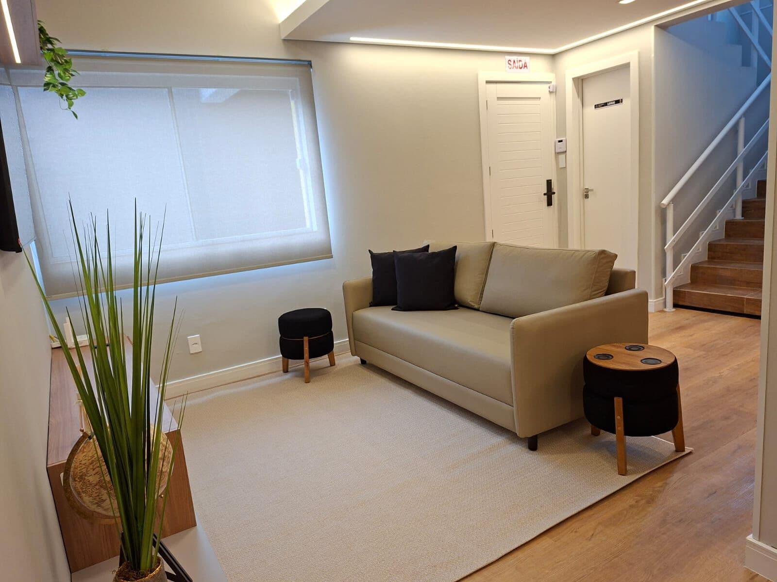 Sala de estar com sofá e acesso à escada
